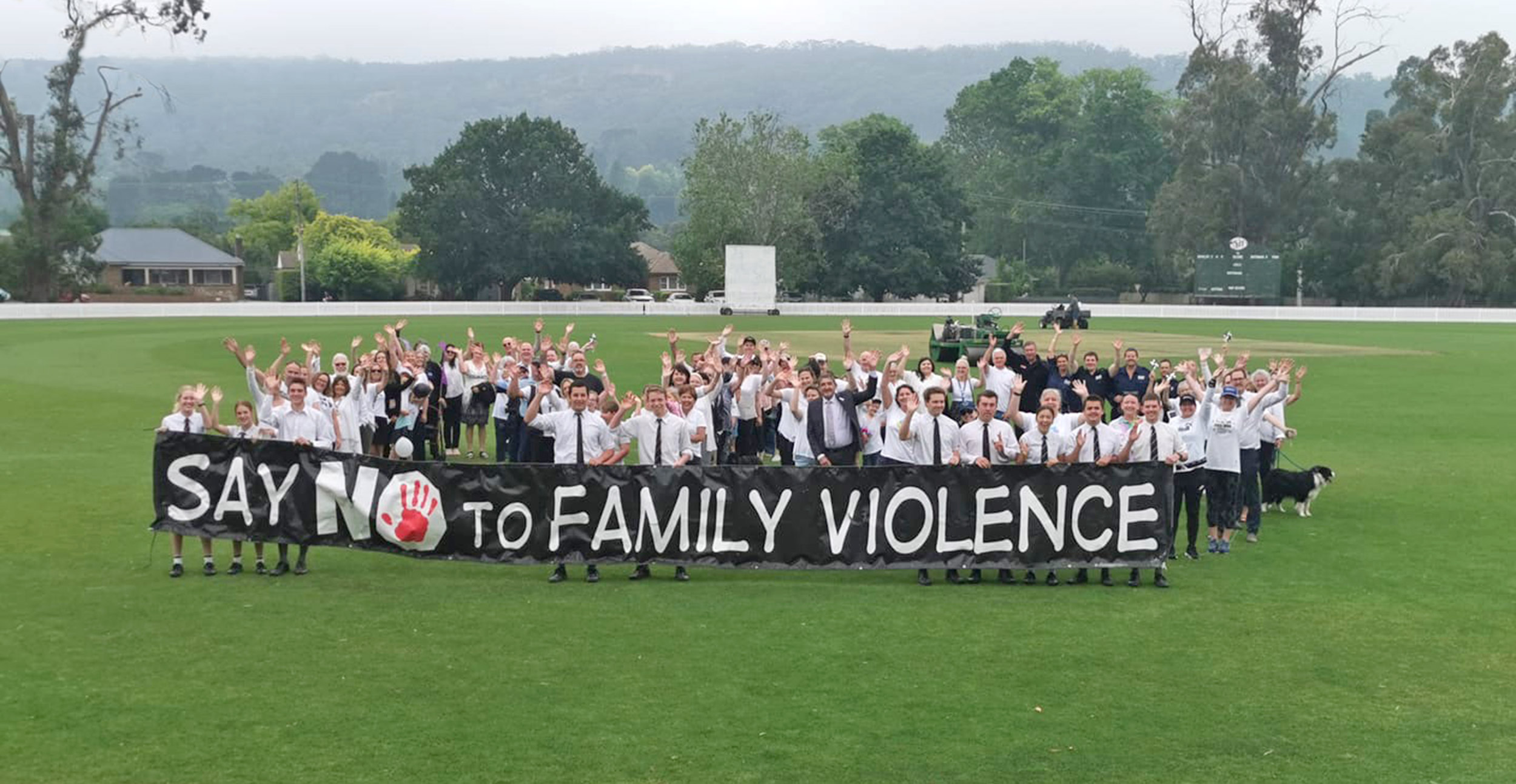 Large group of people holding a banner with words 'Say no to family violence'